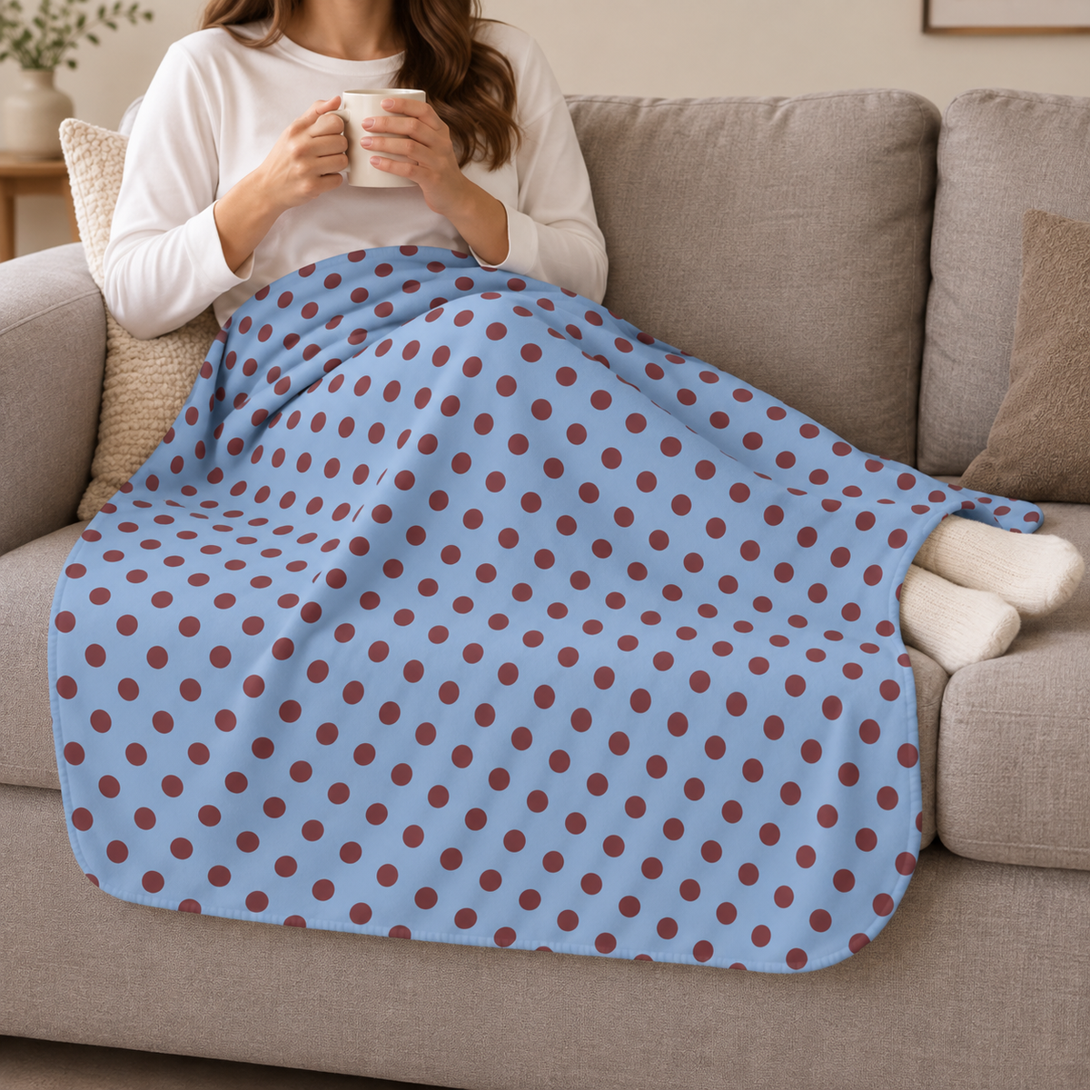 Person relaxing on a couch under the Blue Polka Dot Sherpa Blanket