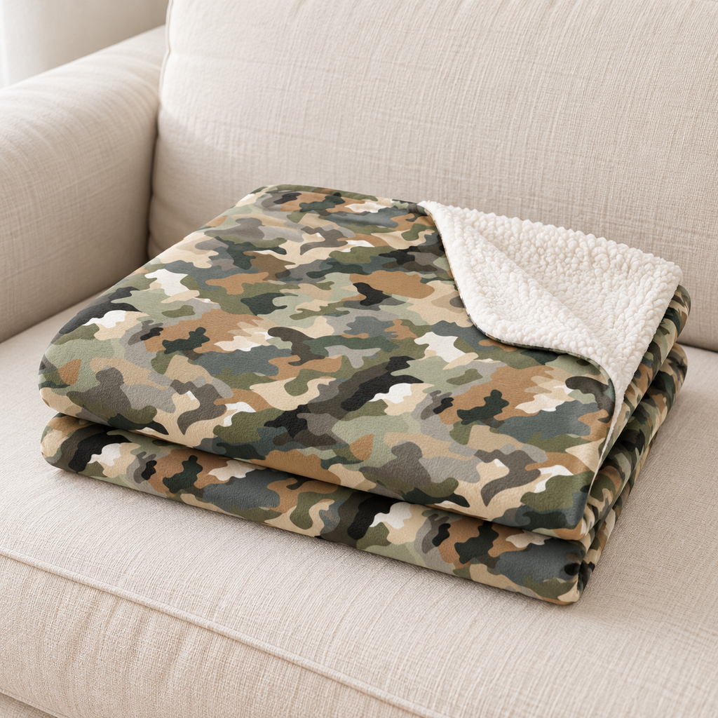 Close-up of the brown camo sherpa blanket folded on a couch, showing the camouflage print and the white sherpa edge
