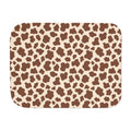 Brown cow print sherpa blanket laid flat, showing chocolate brown patches on a cream ground with a white sherpa edge