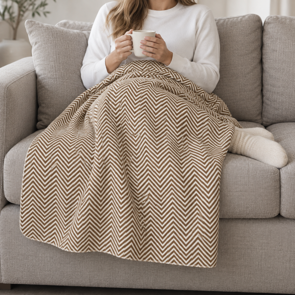 Person relaxing on a couch under the Brown Herringbone Sherpa Blanket
