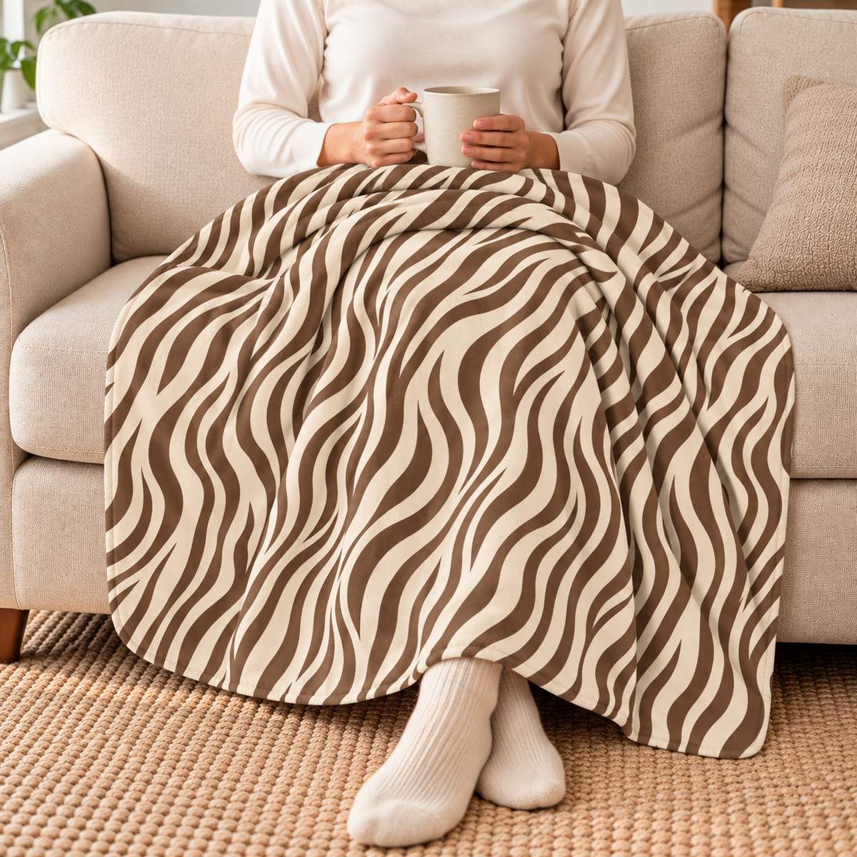 Person relaxing on a couch under the brown zebra print sherpa blanket