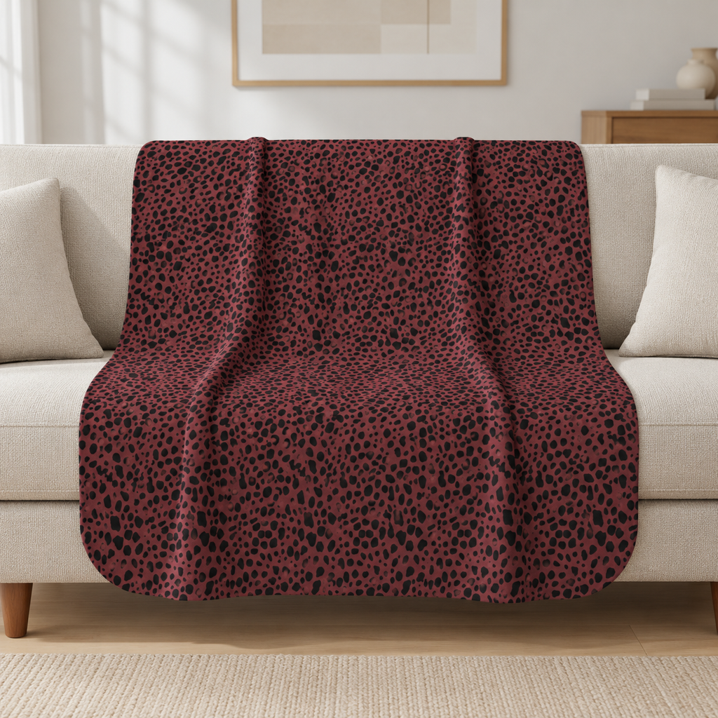 Burgundy Cheetah Print Sherpa Blanket draped over a cream sofa in a living room