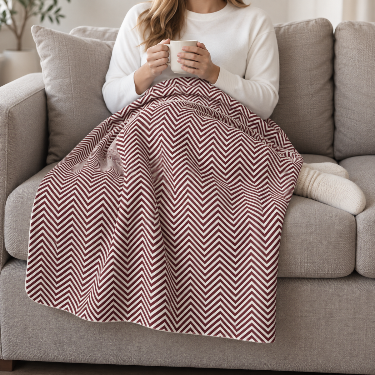 Person relaxing on a couch under the Burgundy Herringbone Sherpa Blanket