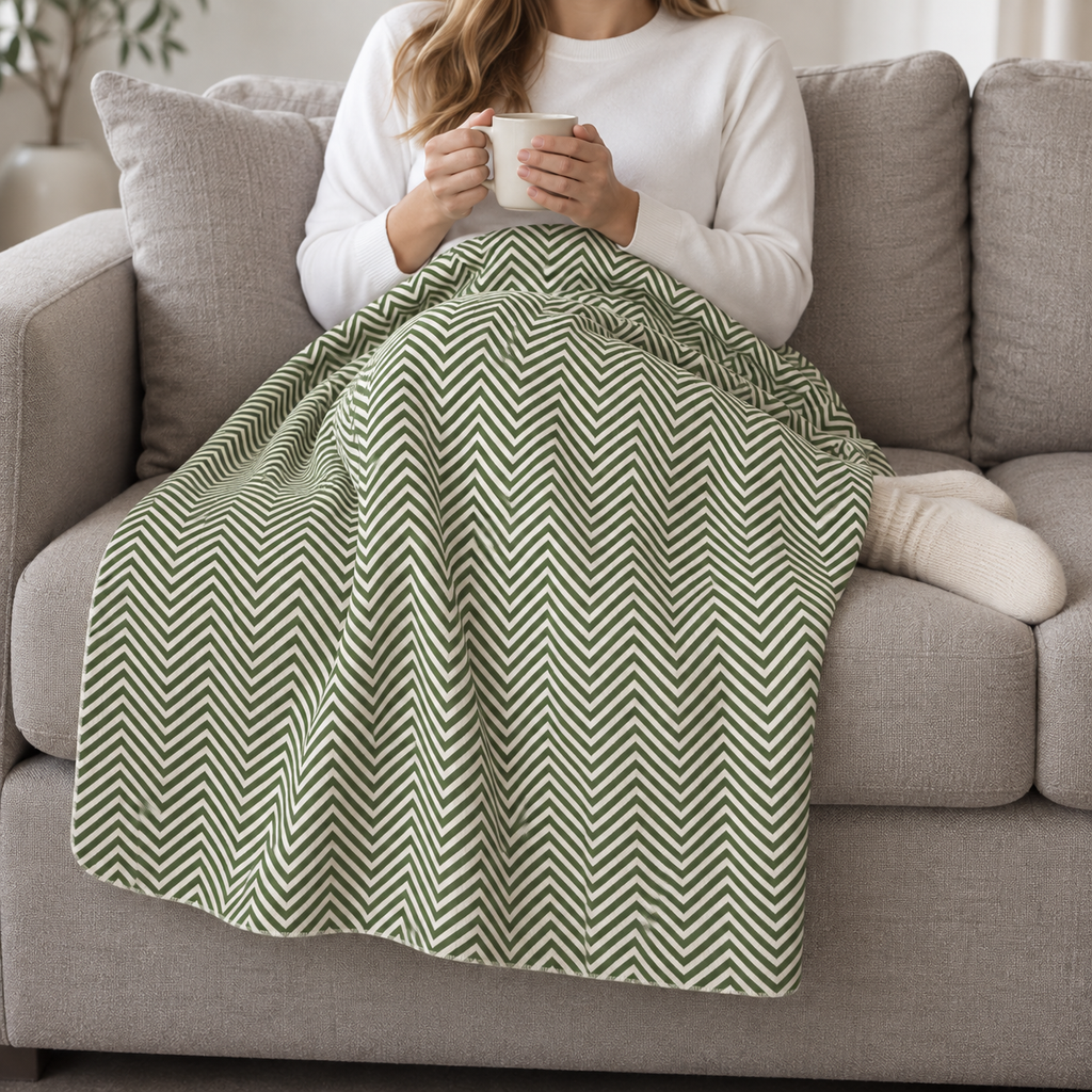 Person relaxing on a couch under the Green Herringbone Sherpa Blanket