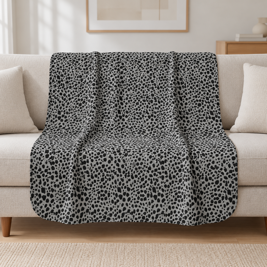 Grey Cheetah Print Sherpa Blanket draped over a cream sofa in a living room