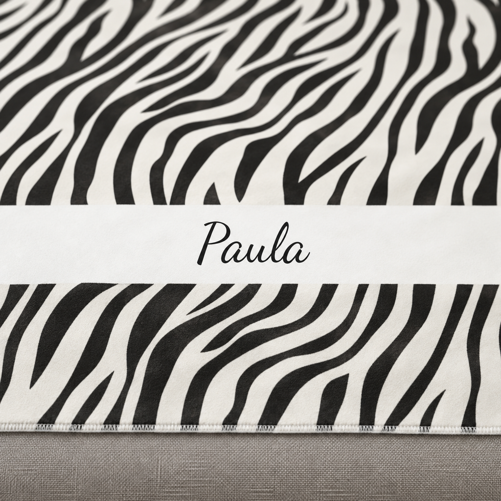 Personalized black and white zebra print sherpa blanket with name, close-up of the name in script on the band