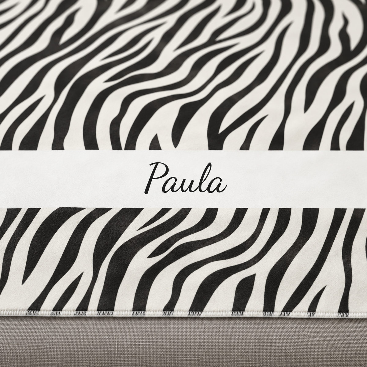 Personalized black and white zebra print sherpa blanket with name, close-up of the name in script on the band