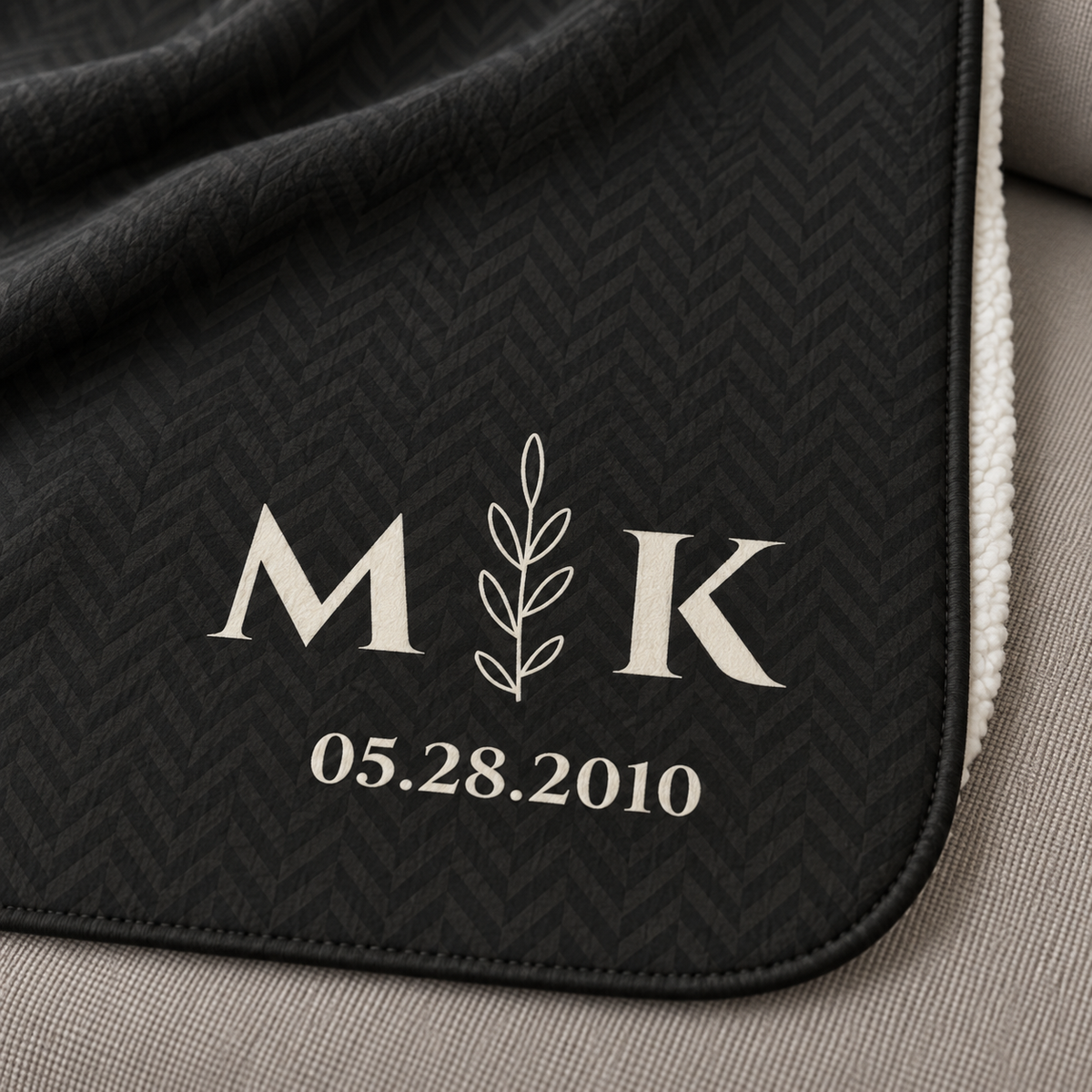 Personalized black sherpa blanket with monogram, close-up of the monogram on the herringbone weave