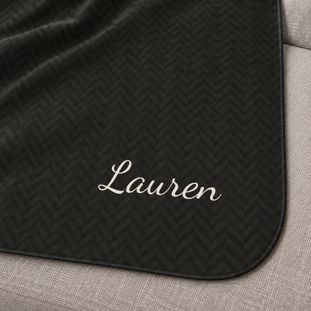 Personalized black sherpa blanket with name, close-up of the name in script on the herringbone weave