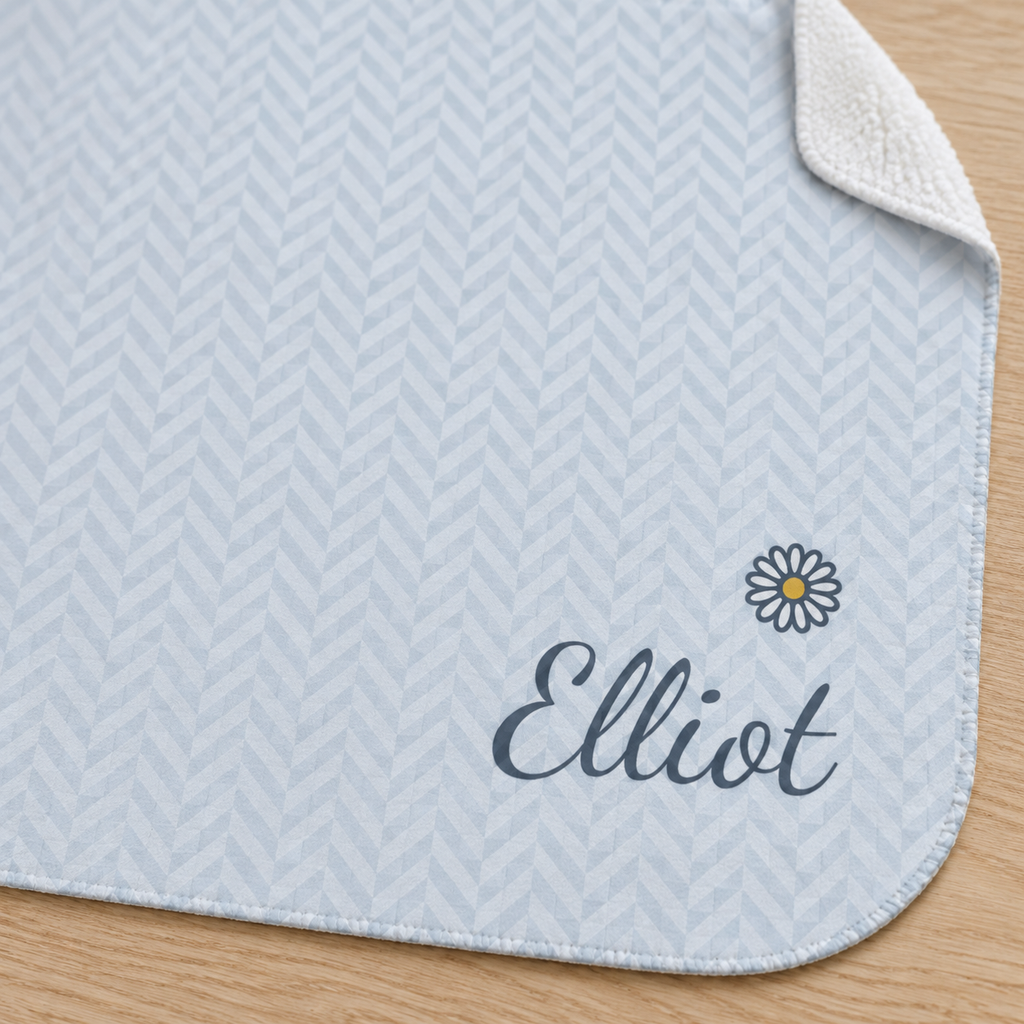 Personalized blue baby blanket with name and a flower, close-up of the name and flower on the herringbone weave