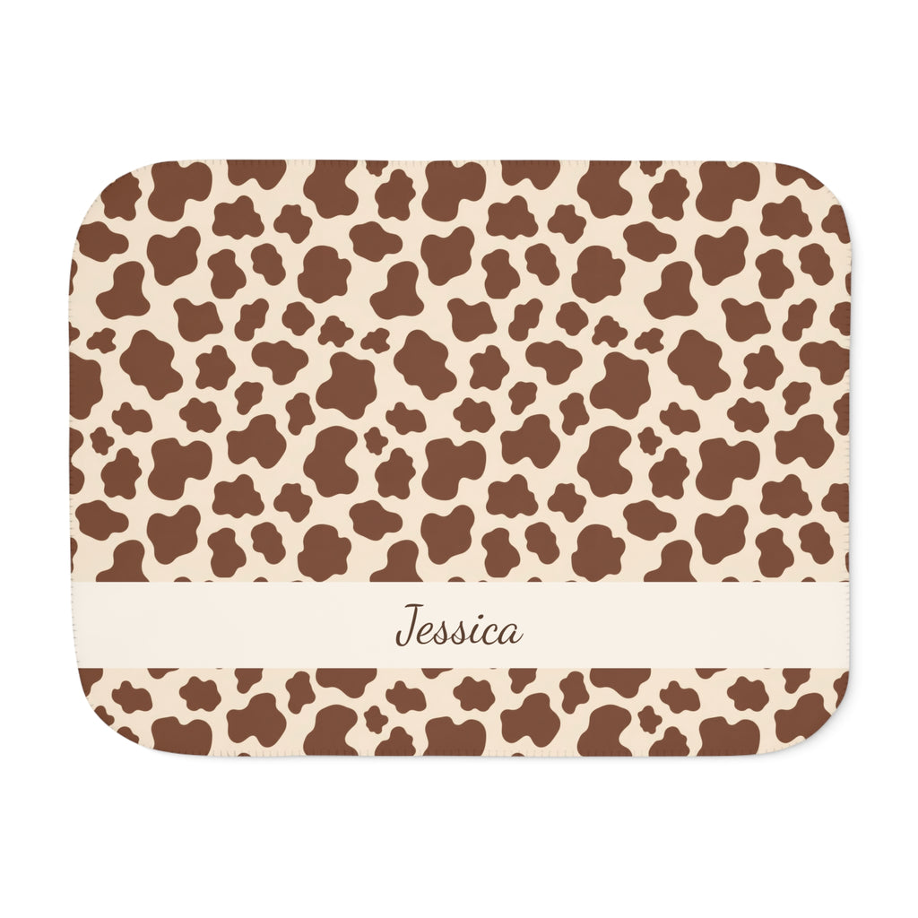 Personalized brown cow print sherpa blanket with name, front view with name band