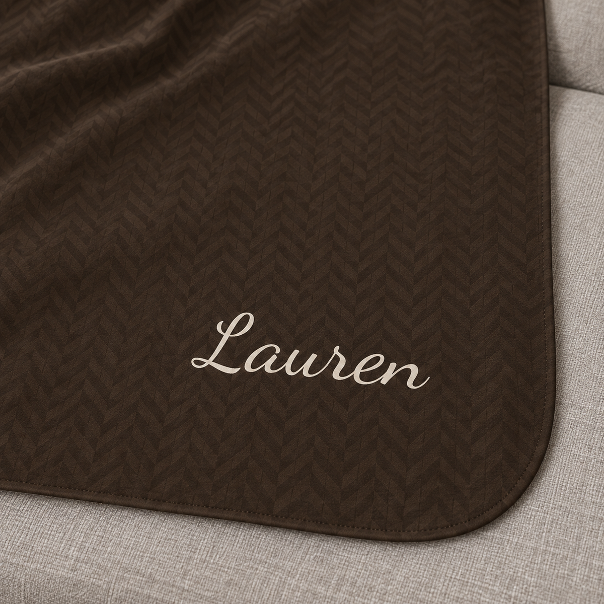 Personalized brown sherpa blanket with name, close-up of the name in script on the herringbone weave