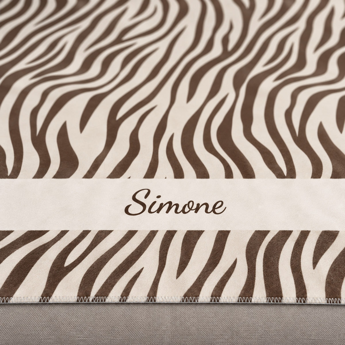 Personalized brown zebra print sherpa blanket with name, close-up of the name in script on the band