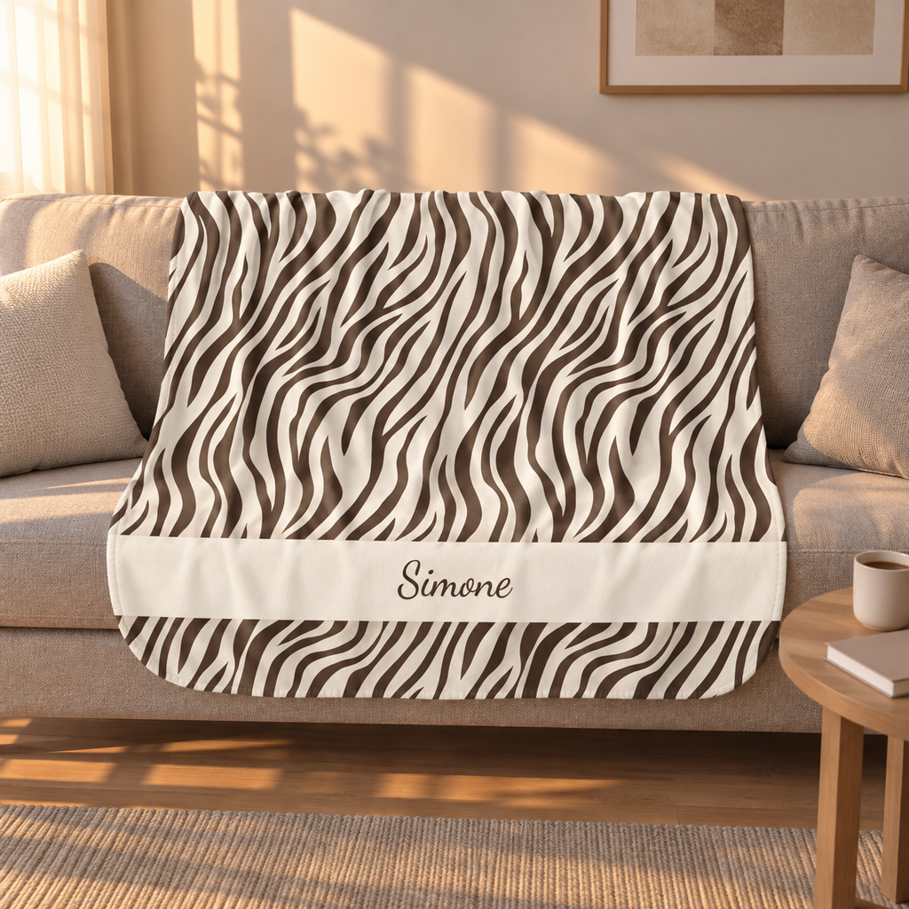 Personalized brown zebra print sherpa blanket with name, draped over a couch