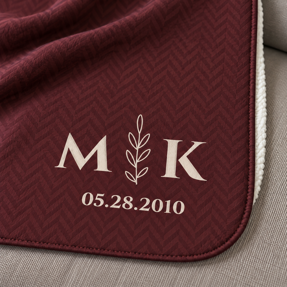 Personalized burgundy sherpa blanket with monogram, close-up of the monogram on the herringbone weave