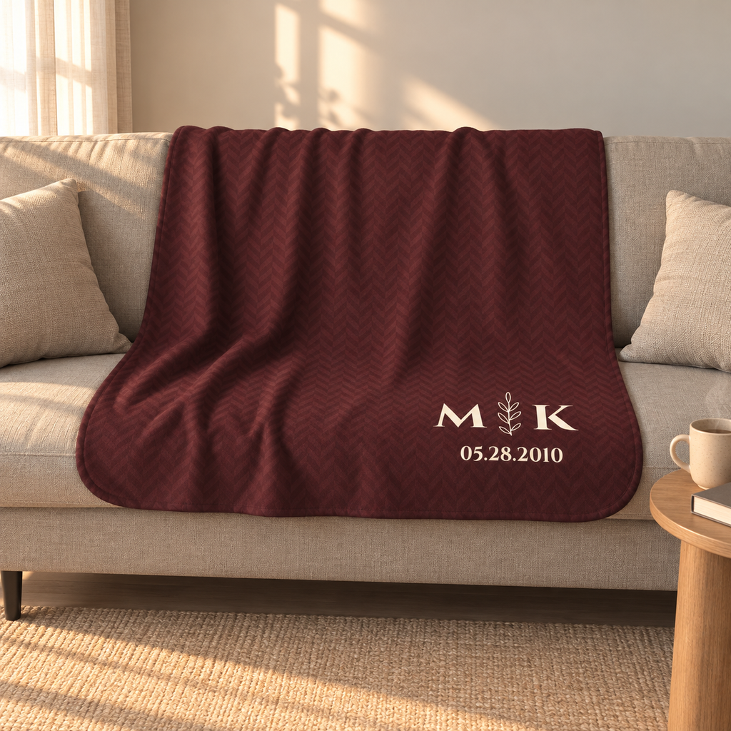 Personalized burgundy sherpa blanket with monogram, draped over a couch