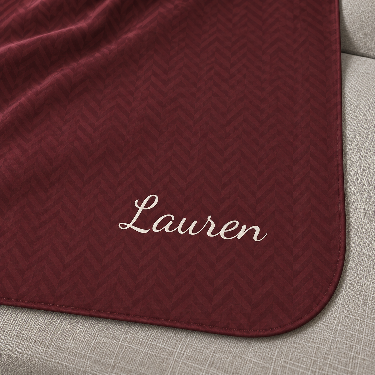 Personalized burgundy sherpa blanket with name, close-up of the name in script on the herringbone weave