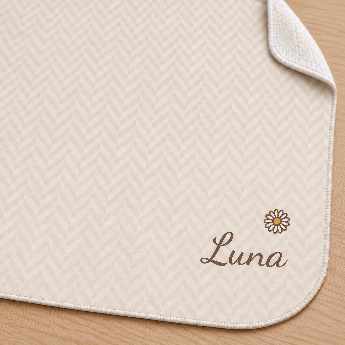 Personalized cream baby blanket with name and a flower, close-up of the name and flower on the herringbone weave