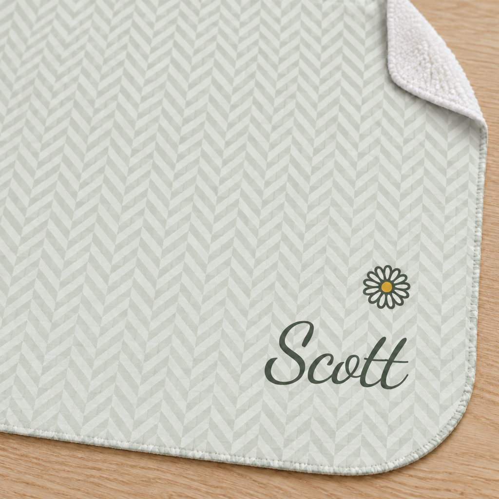 Personalized green baby blanket with name and a flower, close-up of the name and flower on the herringbone weave