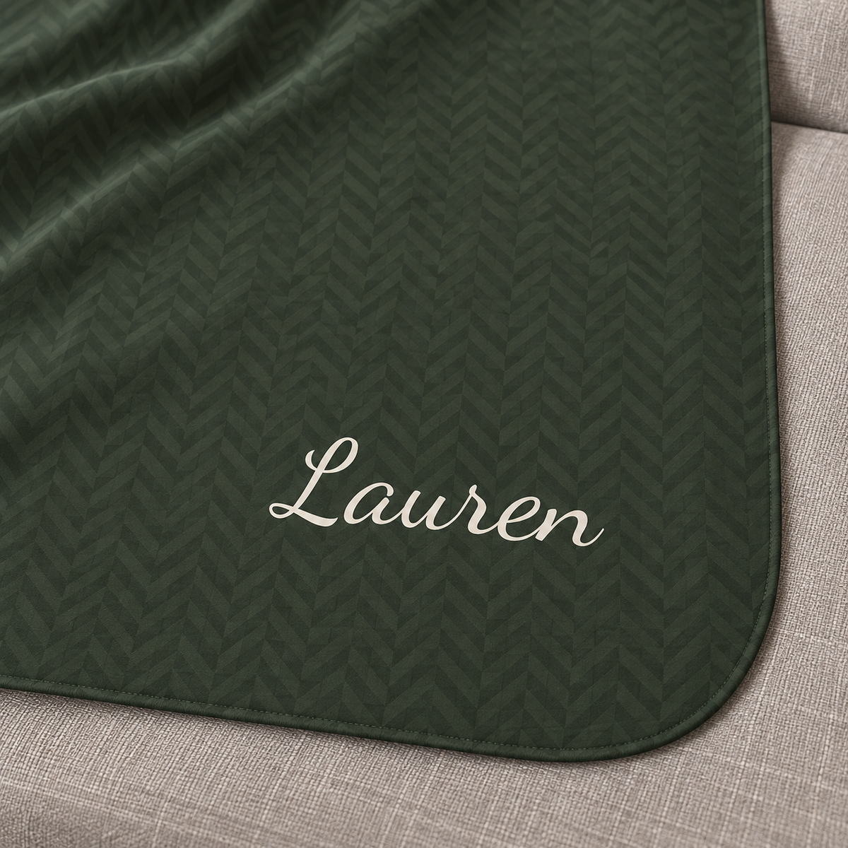 Personalized green sherpa blanket with name, close-up of the name in script on the herringbone weave