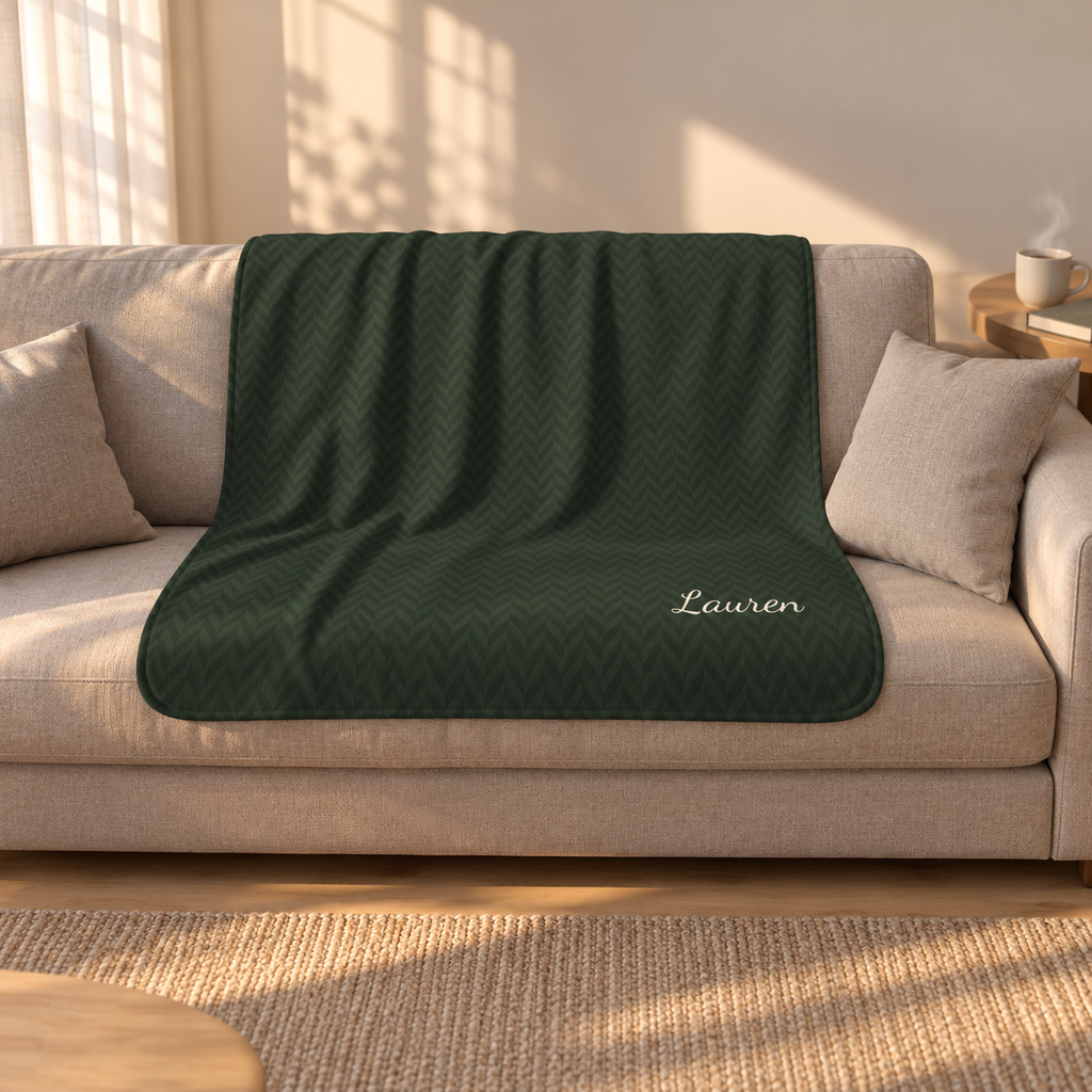 Personalized green sherpa blanket with name, draped over a couch