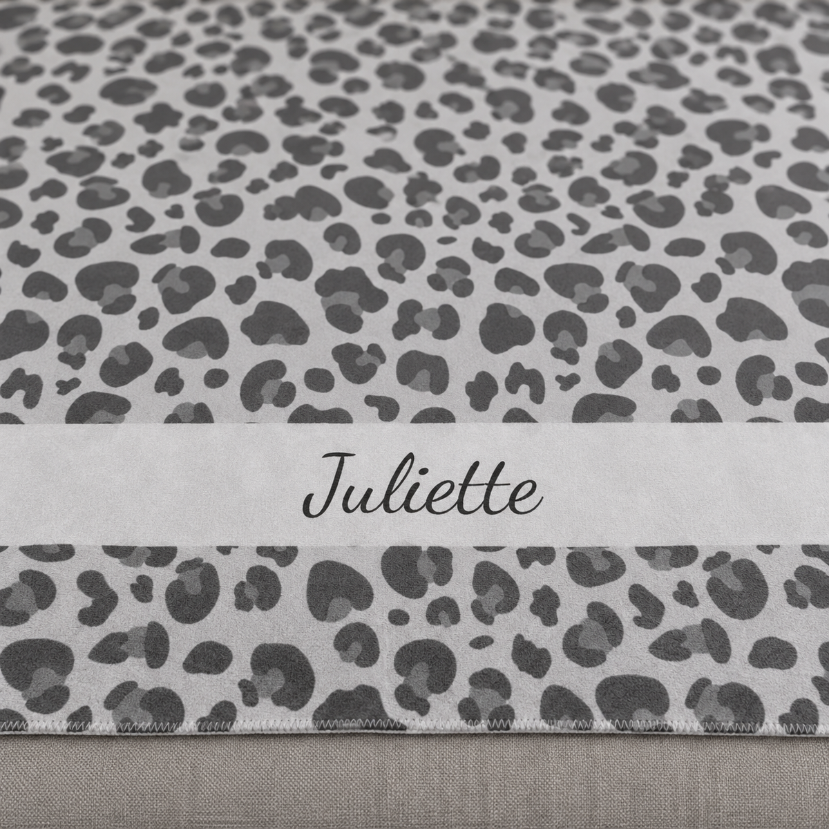 Personalized grey leopard print sherpa blanket with name, close-up of the name in script on the band