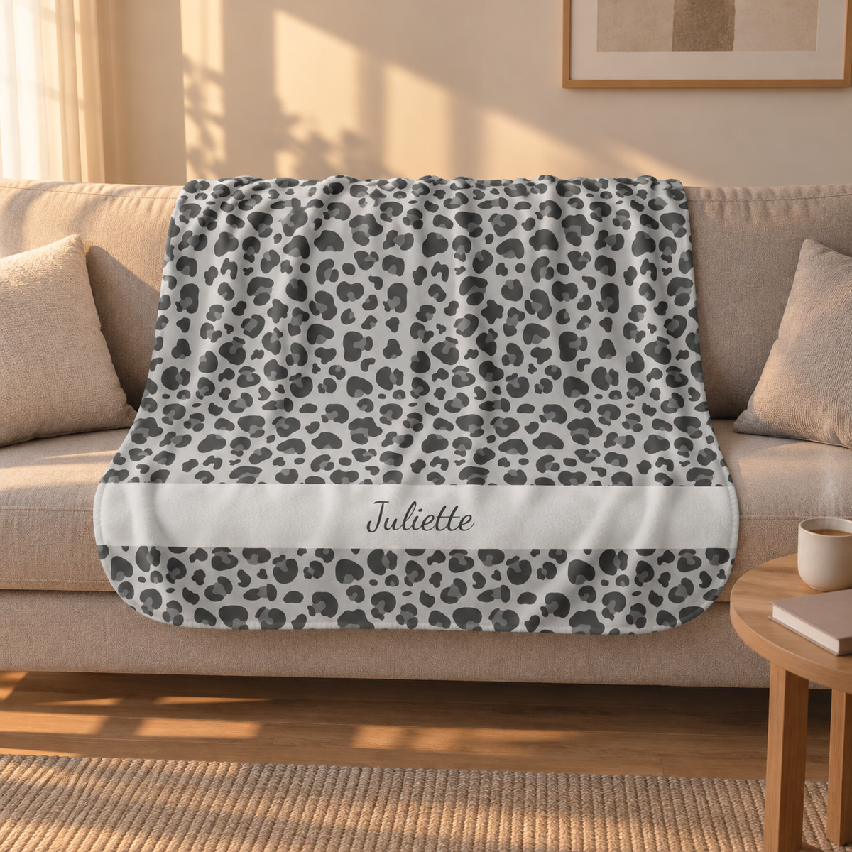 Personalized grey leopard print sherpa blanket with name, draped over a couch