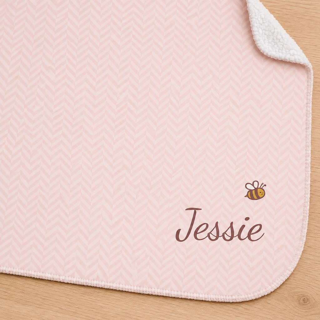 Personalized pink baby blanket with name and a bee, close-up of the name and bee on the herringbone weave