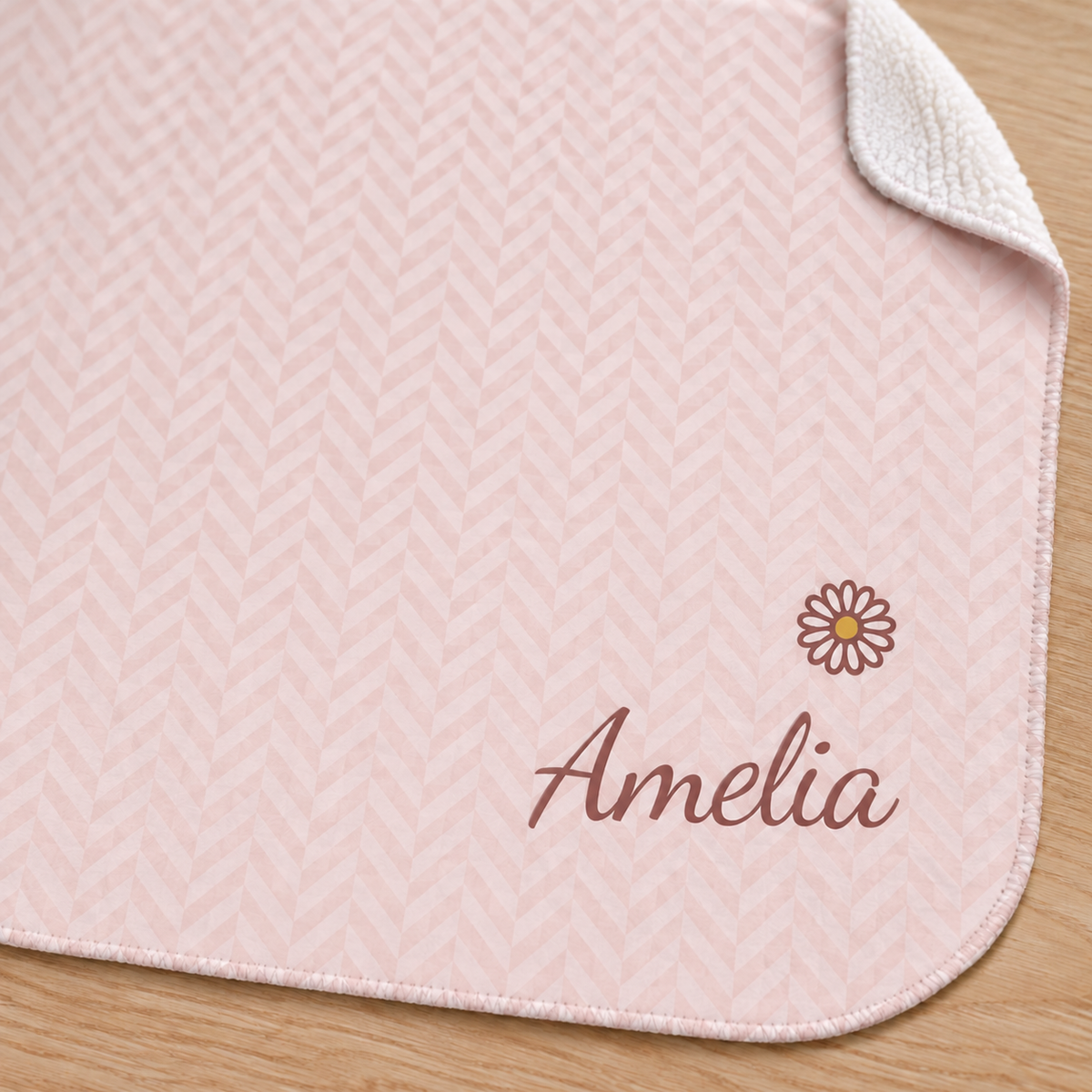 Personalized pink baby blanket with name and a flower, close-up of the name and flower on the herringbone weave