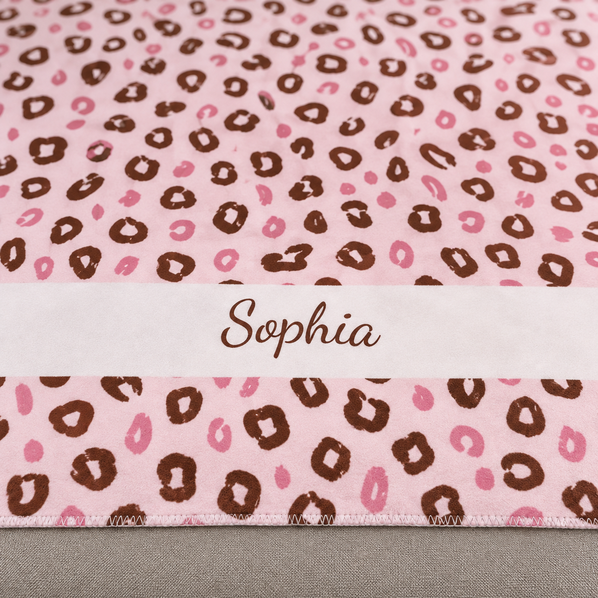 Personalized pink leopard print sherpa blanket with name, close-up of the name in script on the band