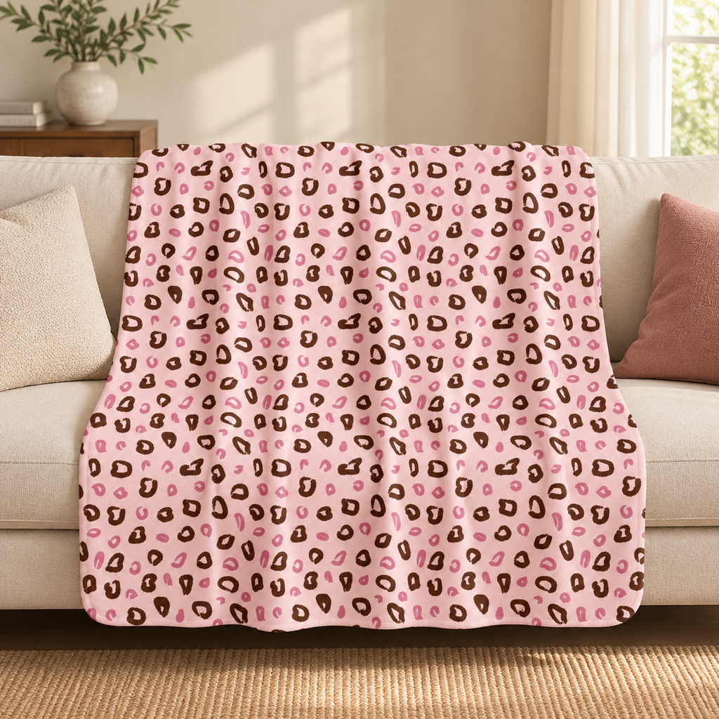 Pink leopard print sherpa blanket draped over a couch in a living room