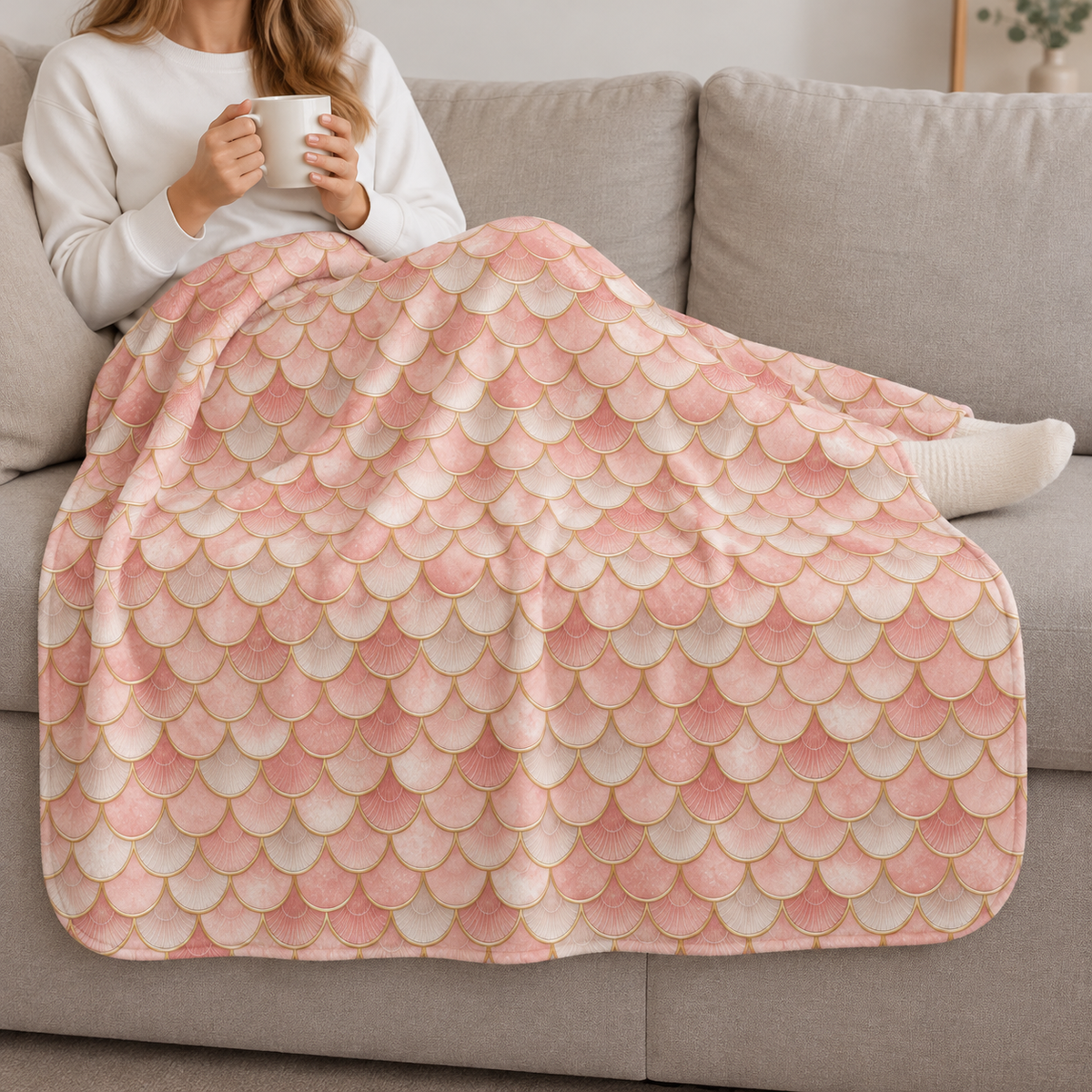 Person relaxing on a couch under the Pink Mermaid Scale Sherpa Blanket